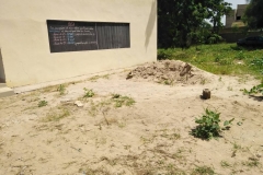 Dass eine Tafel draussen an der Schulwand hängt, hat 2 Gründe. Einer ist, dass die Räume ohne Klimaanlagen oft zu heiß sind und die Kinder deshalb lieber draußen Unterricht haben. Der 2. Grund ist, dass die Schule zu klein ist und deshalb nicht genügend Platz für die Schule hat.