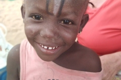 Die Kleine freut sich über die Malkünste der anderen Kinder auf ihrer Stirn. Dafür brauchten sie nur ein Stück Steinkohle aus dem Sand.